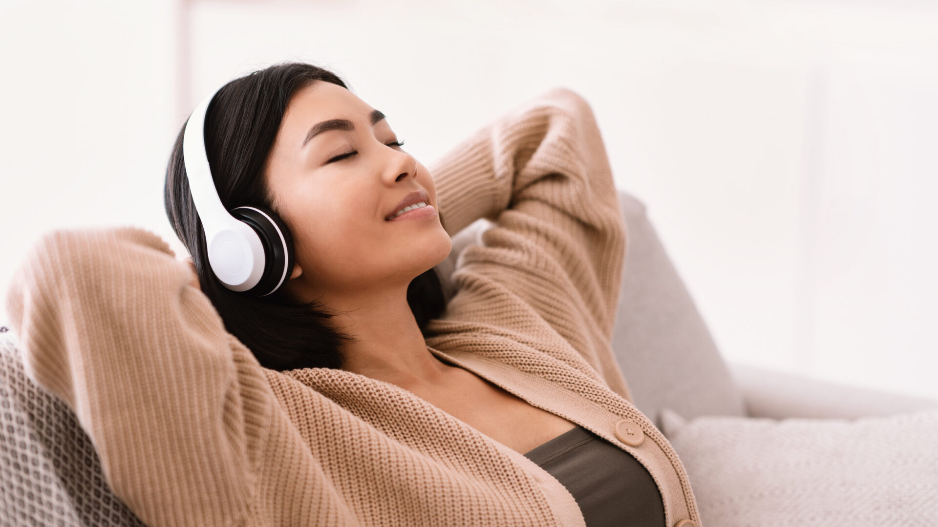 Asian woman listening to music wearing headphones